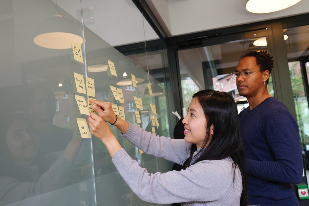 femme collant des post it sur un mur avec un homme à côté 